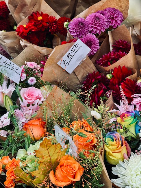 A vibrant display of freshly arranged flower bouquets featuring a variety of blooms including red dahlias, pink and purple chrysanthemums, peach roses, rainbow-tinted roses, and white chrysanthemums. 